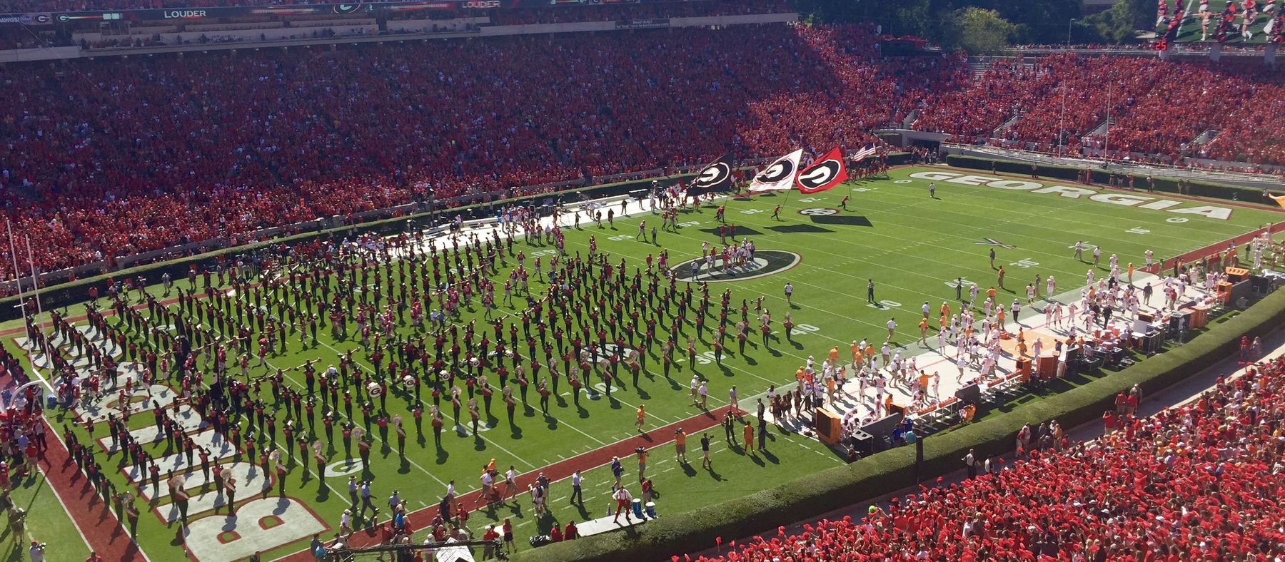 Sanford Stadium packed on a game day, the Redcoat Band in formation on the field and the hedges ringing the grass.