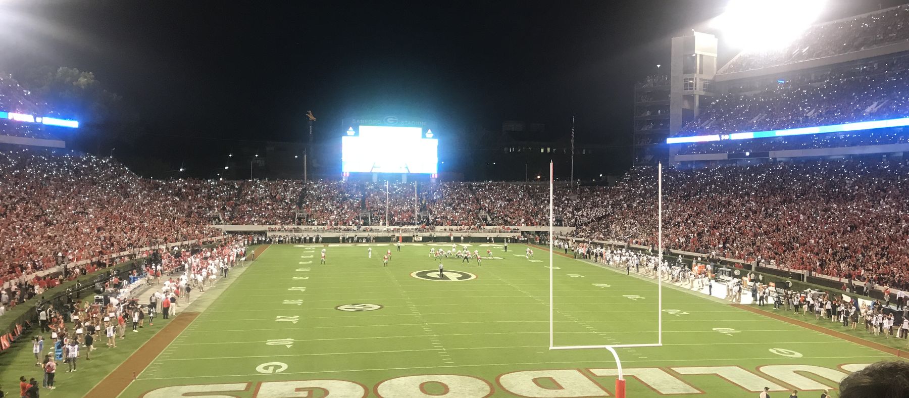 Sanford Stadium under the lights at night, the field glowing green and every seat full.